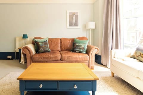 Living Room: Bright space with stylish leather couch, ocean-themed decor, and natural light.