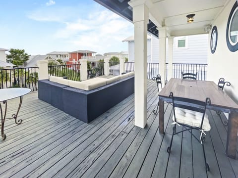 Wooden deck with a couch, table, and chairs located on the 3rd floor