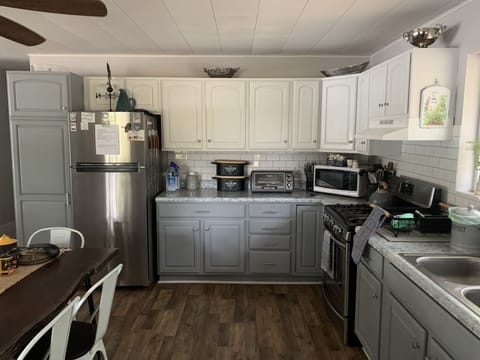 Kitchen stocked with spices, condiments, bakeware, dishes, utensils & glassware.