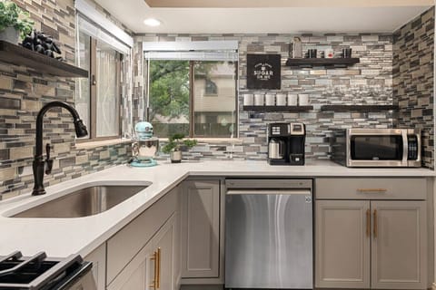 Fully stocked kitchen with mosaic tile backsplash, open shelving, and stainless appliances invites easy mornings and relaxed meals at Good Vibes Roll.