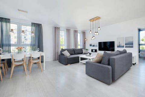 A modern living room with comfortable gray sofas, a coffee table, and large windows providing plenty of natural light.

