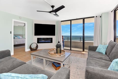 Living room with plenty of seating, ocean views, and 75" TV with fireplace