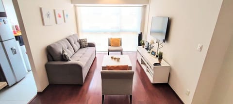 The living room features a spacious layout with ample seating for you and your guests. A large, comfortable sofa and cozy chairs are arranged around a central coffee table, creating a perfect gathering area. 