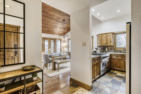 Step into this warm, rustic kitchen where wood cabinets and stone floors create a cozy mountain retreat atmosphere for your culinary adventures.