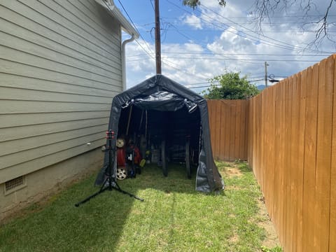 Tarp Shed beside the house in backyard for bike storage