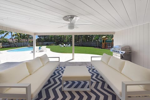 Large covered seating area with ceiling fan and BBQ