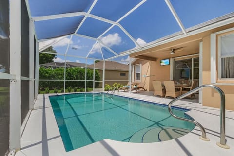Fully screened pool with loungers and outdoor dining and TV