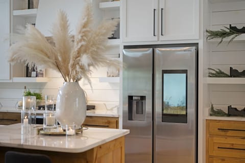 A modern kitchen with double-door stainless steel refrigerators, stylish open shelving, and elegant decor, blending high-end functionality with sophisticated, inviting design.