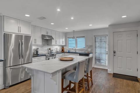 - Oversized marble island with comfy barstool, perfect for casual breakfasts or evening chats
- Fully equipped kitchen boasts stainless steel appliances, vent hood, & open flow design
- Step through to the patio or entry for seamless indoor outdoor living