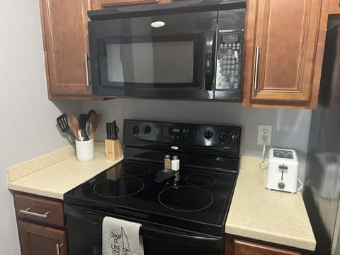 View of kitchen showing stove, microwave, fridge,  toaster, and utensils. 
