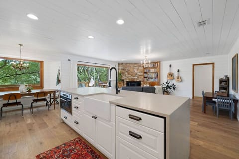 Open kitchen at Serenity on the San Gabriel with farmhouse sink and island overlooking the living room and treetop deck.
