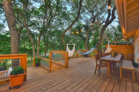 Expansive deck at Serenity on the San Gabriel with hammocks, string lights, and outdoor dining overlooking the river.