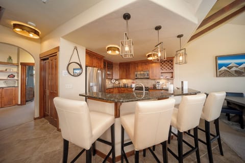 - Kitchen bar with seating for four and pendant lighting above   - Stainless steel appliances and stone counters for easy cooking   - Open design connects to dining and living for shared meals