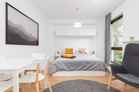 Well-lit bedroom featuring modern furniture and expansive windows with a view.
