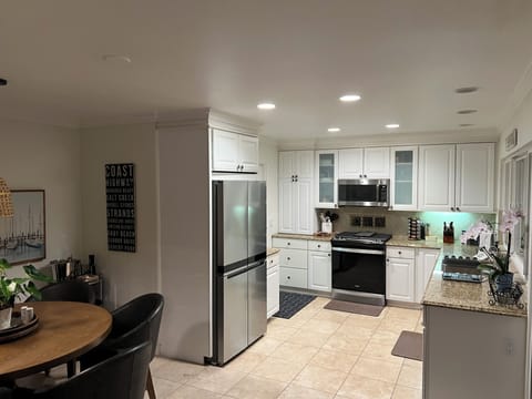 Kitchen area with refrigerator, gas stove/range and door leading to the garage.