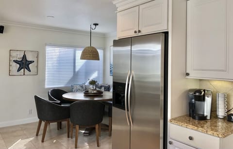 Coffee bar and frig adjacent to dining area with window onto courtyard entrance.