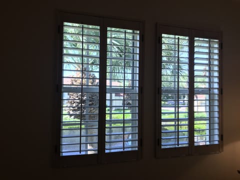 Master bedroom windows with plantation shutters overlooking lake.