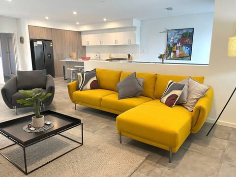Discover ultimate comfort in our cozy living room, featuring a plush sofa perfect for relaxation. This inviting space seamlessly connects to a modern, well-appointed kitchen, ideal for social gatherings and easy meal preparation.