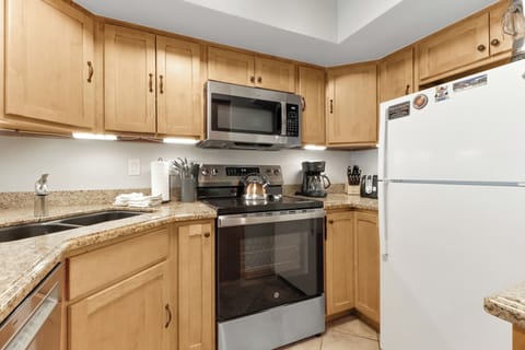 Your fully-equipped kitchen awaits with warm wood cabinets and granite countertops, complete with everything you need to whip up delicious meals during your stay.
