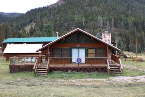 A rustic mountain cabin with expansive front deck sits nestled in a forested valley, offering scenic privacy and access to wooded trails.