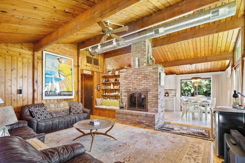 Living room with brick fireplace, vaulted wood-plank ceiling, and garden views