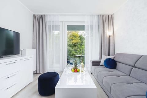 A bright living room with a comfortable gray sofa, a coffee table, and large windows providing natural light.