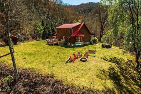 An elevated view shows the log cabin, broad grassy yard, outdoor seating, and wooded mountain setting. This secluded Bryson City cabin offers open space in the Smoky Mountains.