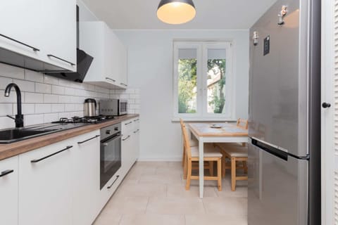 A fully equipped kitchen with white cabinets, a large stove, and a window letting in daylight.
