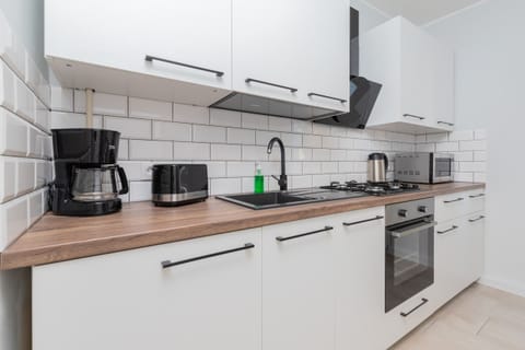 A fully equipped kitchen with white cabinets, a large stove, and a window letting in daylight.
