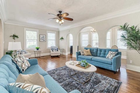 A spacious and elegant living room invites you in with its soaring ceilings, intricate crown molding, and gleaming hardwood floors. Abundant natural light streams through large windows, casting a warm glow on the inviting space. 