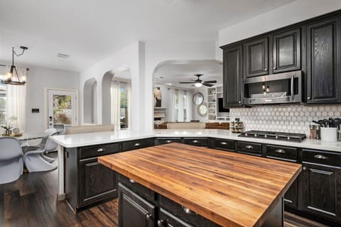 Modern kitchen featuring gas range, microwave, large butcher-block island, and generous counter space for preparing meals together.