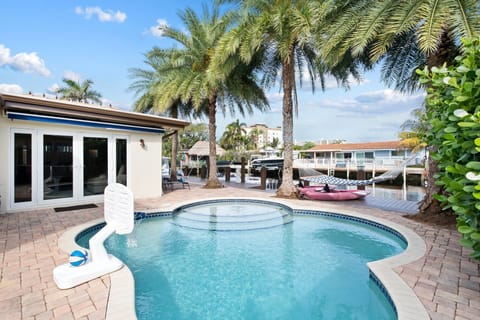 Relax in the private backyard, with amazing waterway views day & night and amenities that include a heated pool, large tiki hut with dining table and outdoor TV, 2 kayaks, BBQ grill,  comfortable lounge & dining seating all surrounded by tropical lan