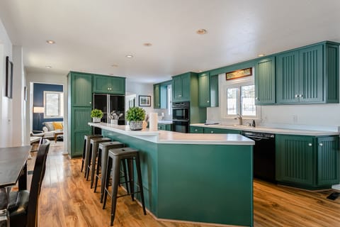 Large, fully stocked kitchen includes microwave, oven, stove, fridge, dishwasher, and laundry. Bar stools and counter-height table provide seating for 7.