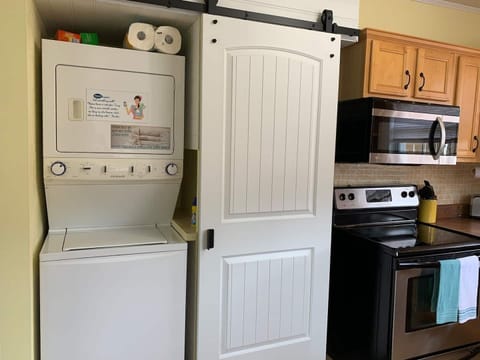 Stackable washer and dryer is tucked away behind the barn door