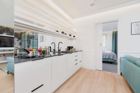 Functional kitchenette with white cabinets. There is a mirror on the wall above the cabinets. High-quality appliances ensure that home-cooked meals can be prepared.