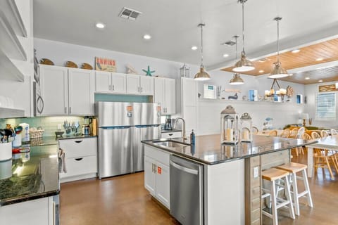 Bright, beachy kitchen with island seating and modern appliances—ideal for group meals.