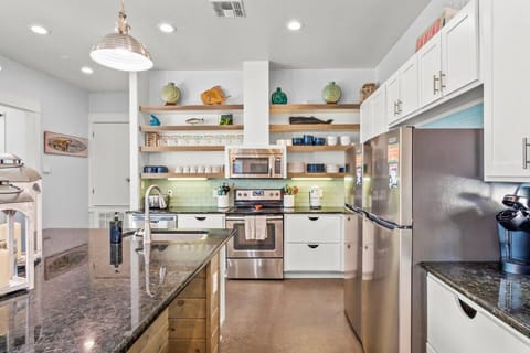 Fully stocked coastal kitchen with modern appliances and open shelving for a home-away-from-home feel.