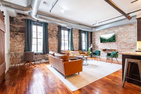 Open-concept living and dining area with exposed brick and large windows