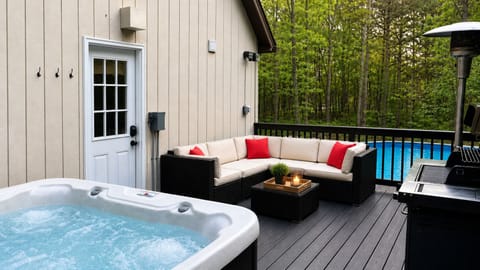 Relax on the private lodge deck featuring a hot tub, BBQ grill, and cozy seating