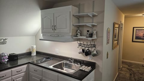 Kitchen with sink, garbage disposal, cooktop, mugs and dishes
