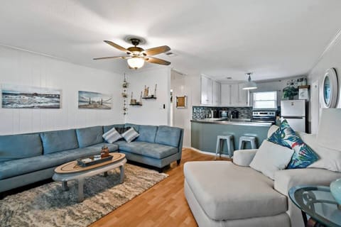 Sunlit space with plush seating, nautical decor, and a seamless kitchen connection!