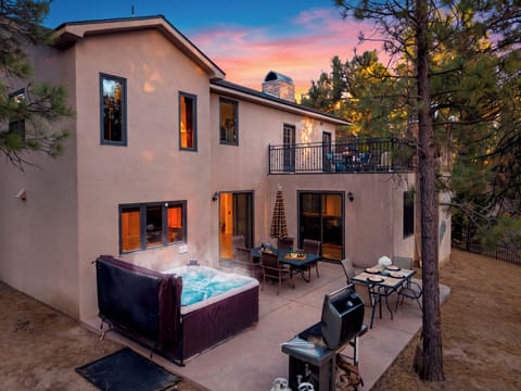 Twilight mountain charm with a bubbling hot tub, outdoor dining, and a private pine-lined patio.