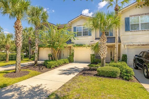 Two-story property exterior with palm trees and double garage