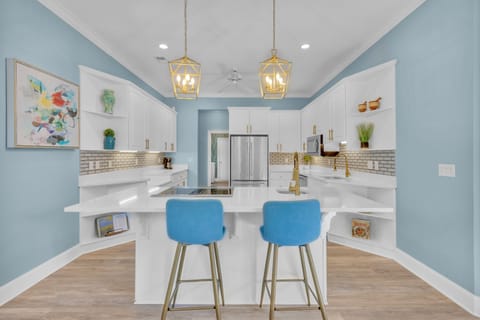 Spacious kitchen with stainless steel appliances, ample counter space, fully stocked essentials, and three barstools for additional seating.