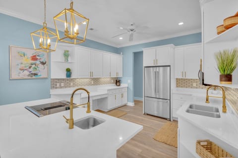 Spacious kitchen with stainless steel appliances, ample counter space, fully stocked essentials, and three barstools for additional seating.