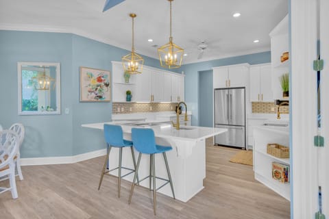 Spacious kitchen with stainless steel appliances, ample counter space, fully stocked essentials, and three barstools for additional seating.