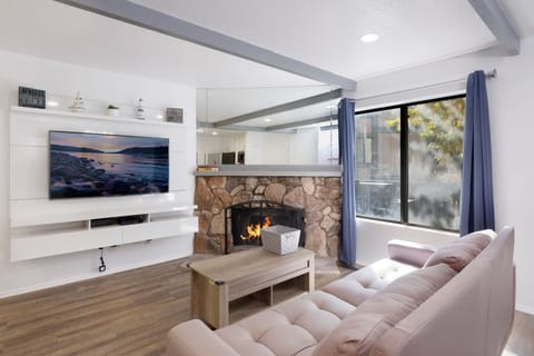 Cozy mountain living room with  a stone fireplace, comfy seating, and smart TV—perfect for relaxing evenings, movie nights, and warm cabin vibes after outdoor adventures.