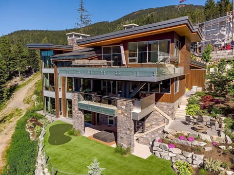 Trails End Estate in Summer featuring the golf putting green, multiple terraces with fireplaces.