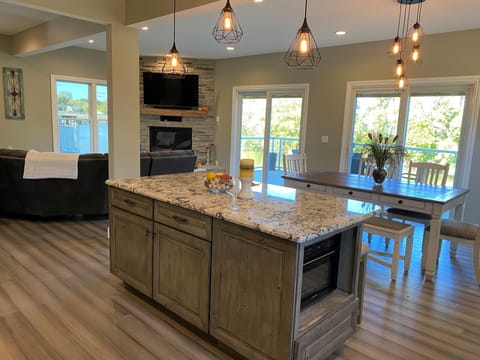 Gourmet kitchen with island, dining area and living area with cozy fireplace.