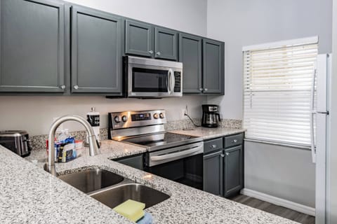 Welcome to this beautifully designed kitchen with rich navy cabinetry and speckled granite countertops. Enjoy the convenience of modern stainless steel appliances, complemented by natural light that creates an inviting atmosphere.